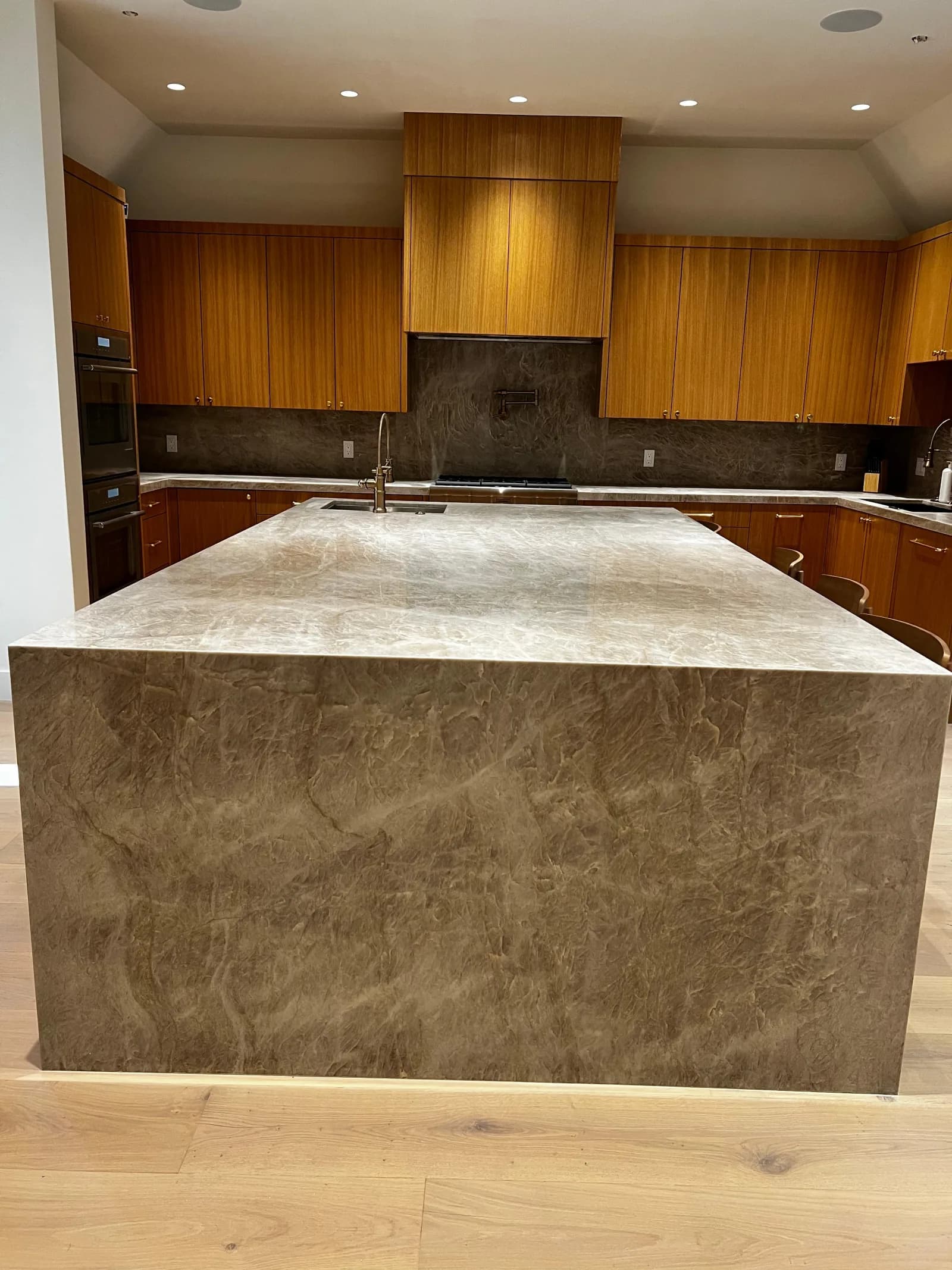 Custom kitchen with waterfall marble island and wood cabinetry
