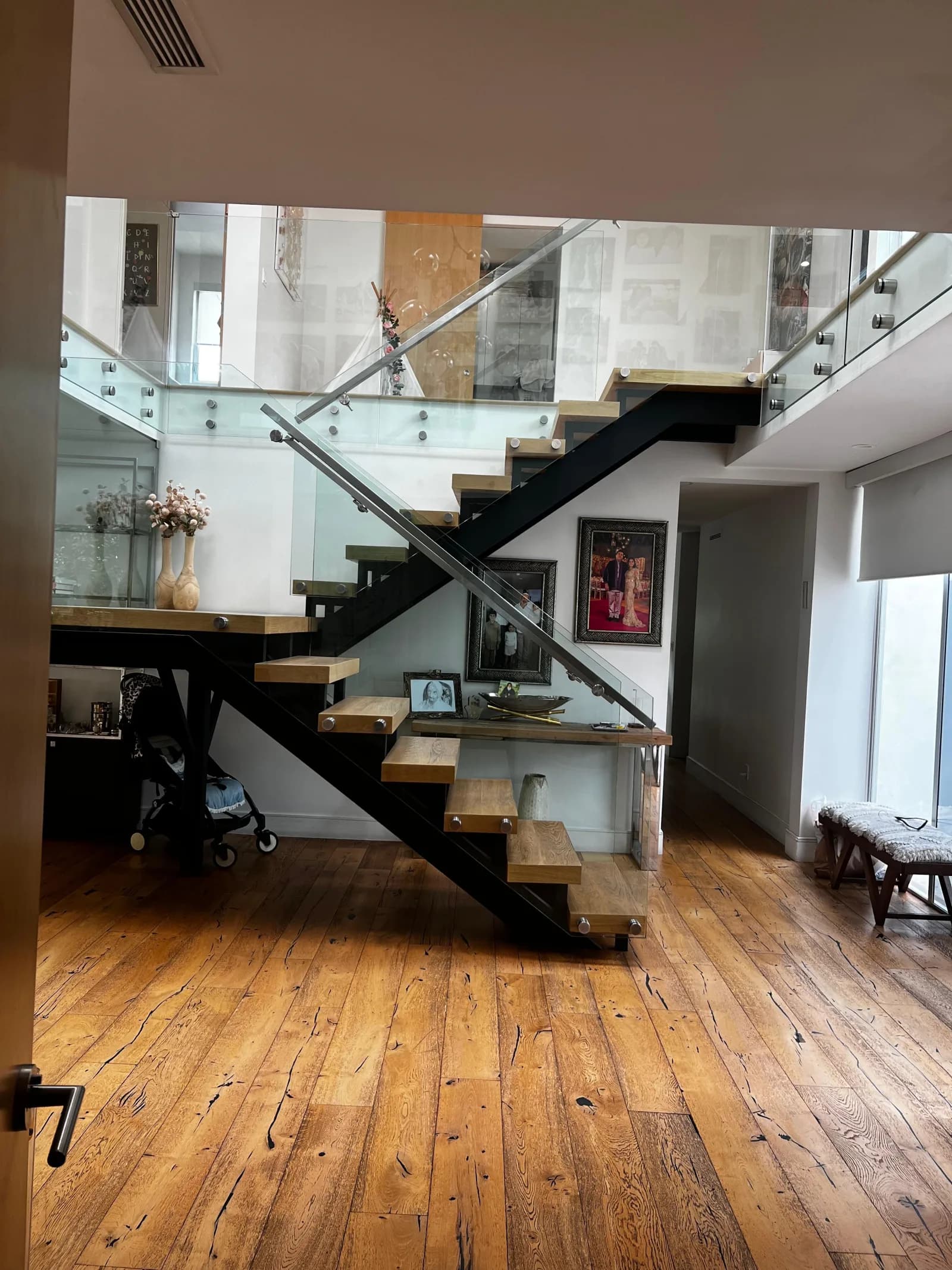 Floating staircase over reclaimed wood floors with glass guard